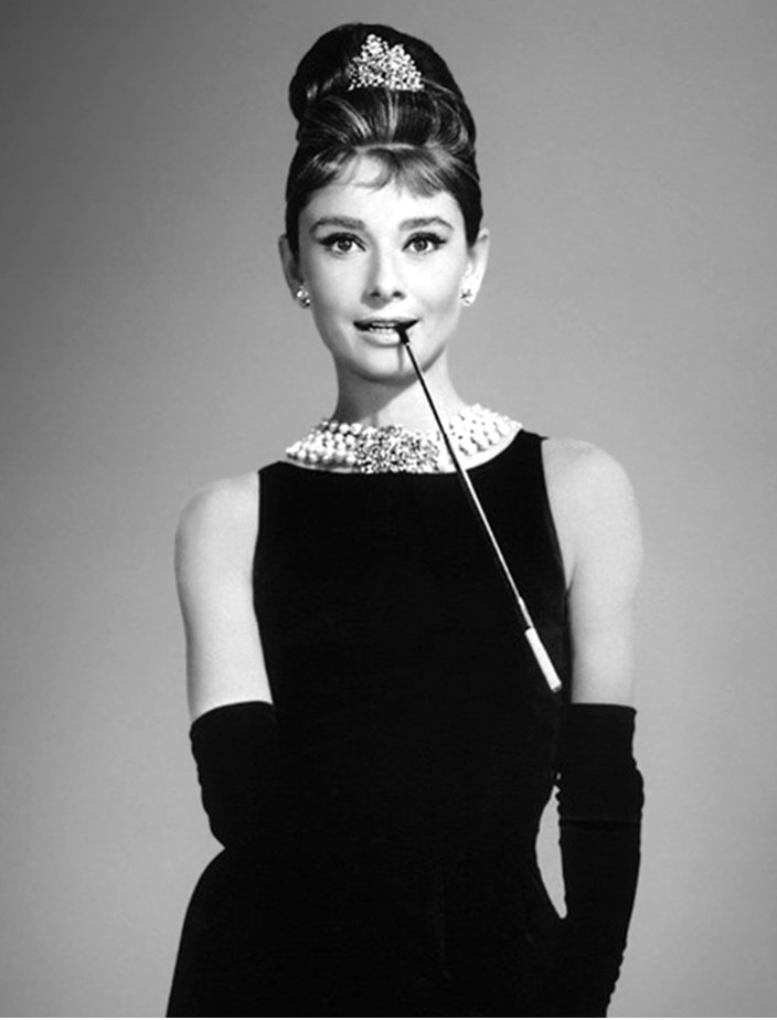 Audrey Hepburn com colar de pérolas e vestido preto icônico.