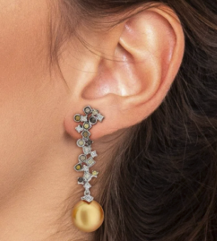 Brinco com pérola dourada e detalhes ornamentados em orelha feminina