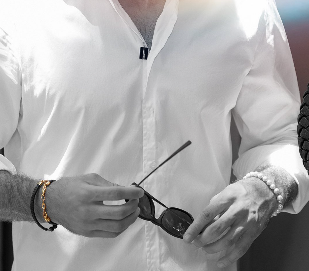 Close de homem usando combinação de pulseiras masculinas, expressando estilo e sofisticação.