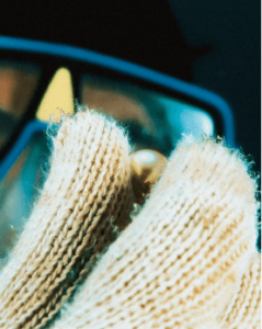 Pessoa limpando uma pérola com um pano de algodão, usando luvas e óculos de proteção.