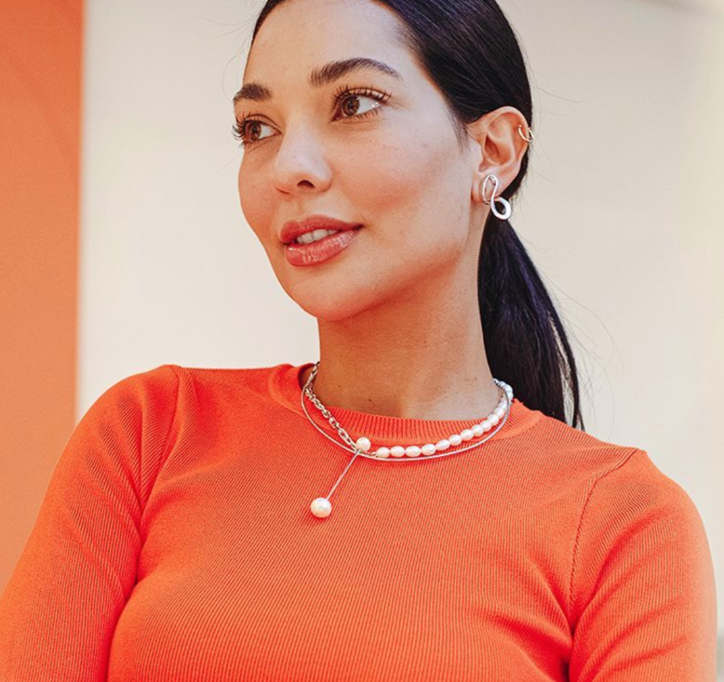 Mulher elegante usando colar de prata com pérolas e brincos delicados, destacando seu visual moderno com um toque de sofisticação.