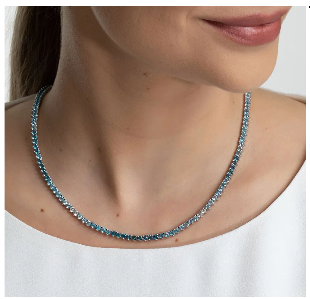 Mulher usando colar Riviera em ouro branco com topázios azuis e topázios brancos.