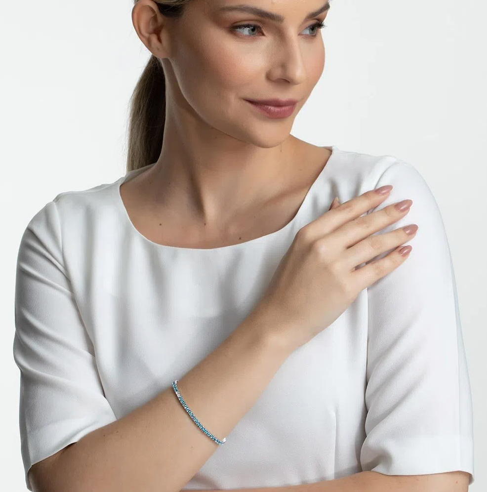 Mulher usando pulseira Riviera em ouro branco com topázios azuis e topázios brancos.